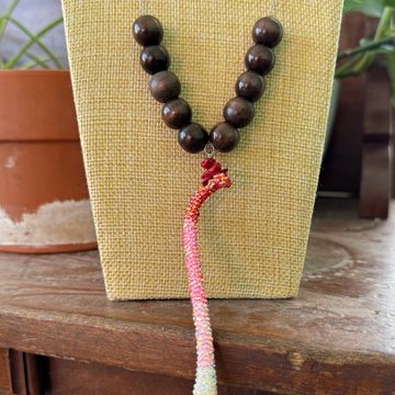 Wooden bead necklace with colorful braided tassel on display.
