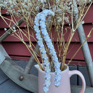 White beaded earrings hanging on dried flowers in a pink vase.