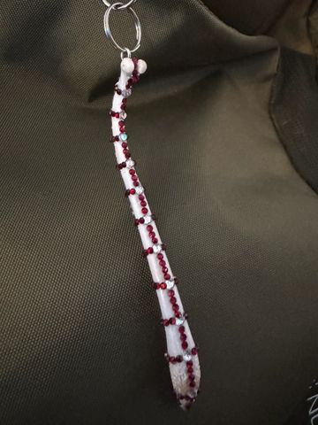 Decorative white bone keychain adorned with red and silver beads.
