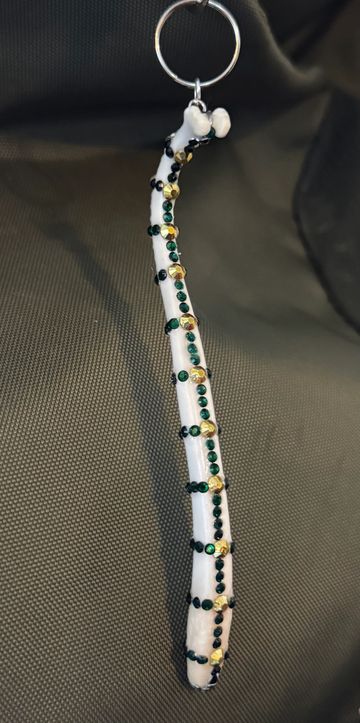 Decorative white keychain adorned with green and gold beads.