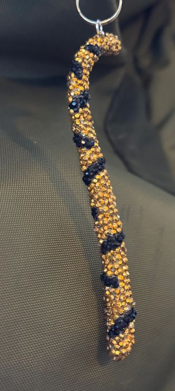 A sparkly snake-shaped keychain with gold and black rhinestones.