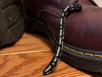 Close-up of a boot with a black and white beaded bracelet hanging from it.