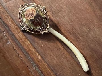 Vintage hairpin with floral design on wooden surface.