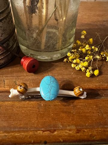 Decorative hairpin with beads and a blue stone on a wooden table.