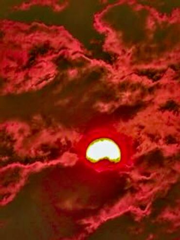 Sun surrounded by red clouds at sunset.