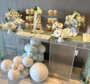 Elegant dessert table with white treats and floral decorations.
