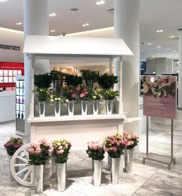 White flower cart with pink and white flowers indoors.
