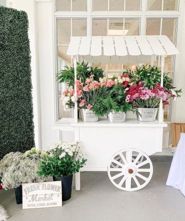 White flower cart with colorful flowers.