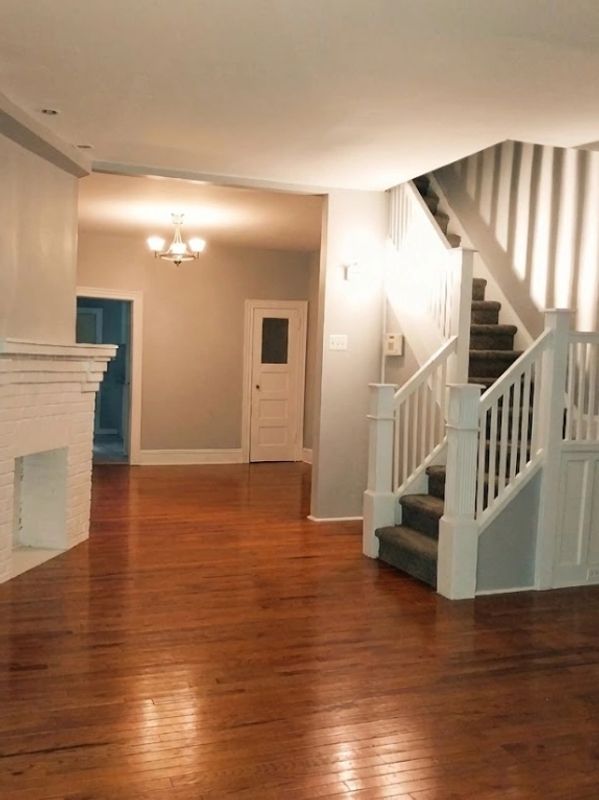 Empty living room with wooden floors and carpeted stairs.