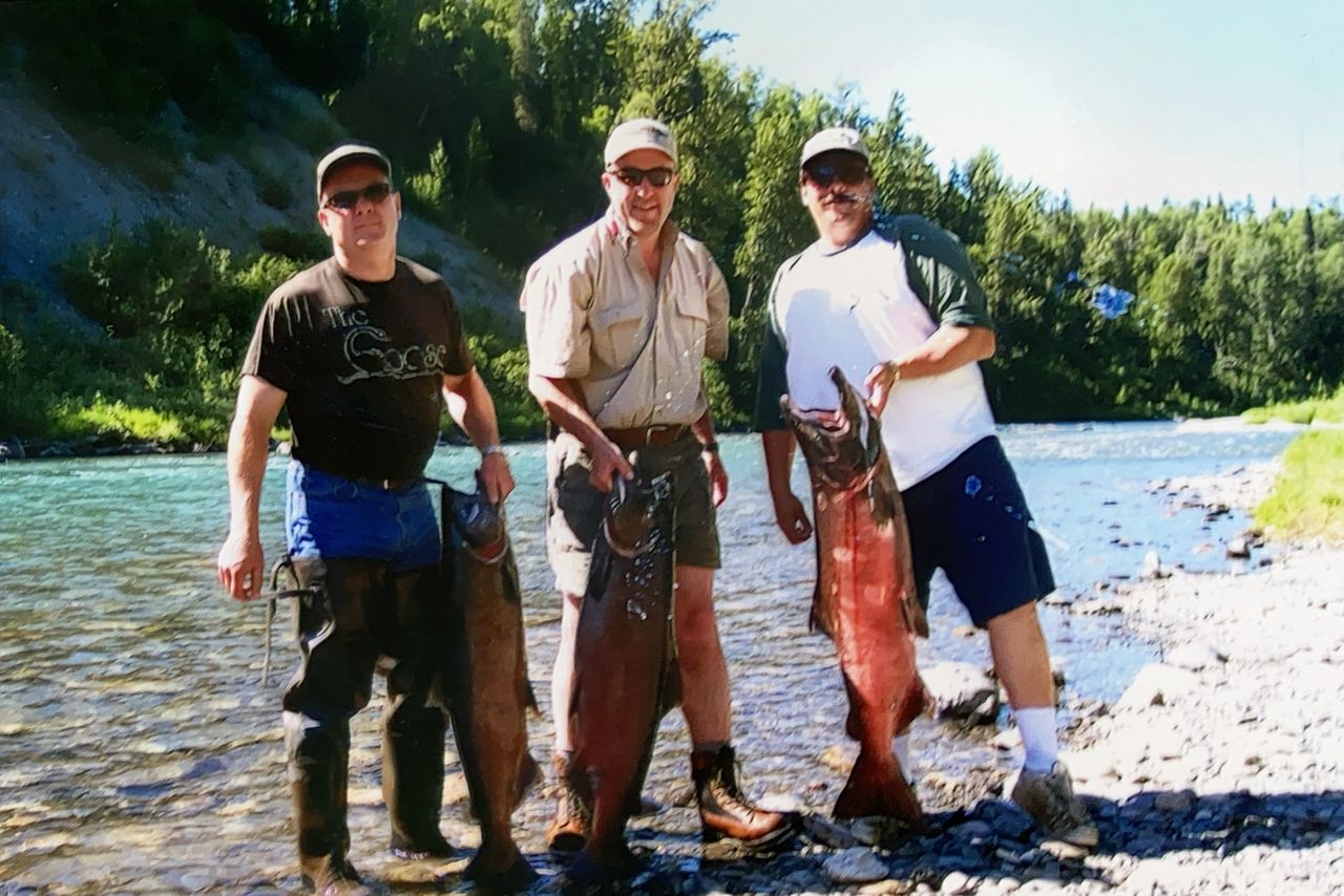 Three fishermen held king salmon on an Alaskan remote riverbank
