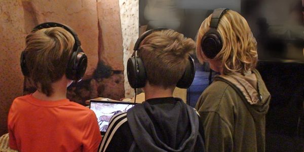 Are children wearing headphone and Watching the video on the tab