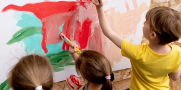 Niños pintando en una pared con colores brillantes.