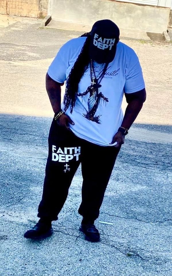 Owner Shott Brown wearing the classic walk by faith tee and faith Dept.black joggers and trucker hat