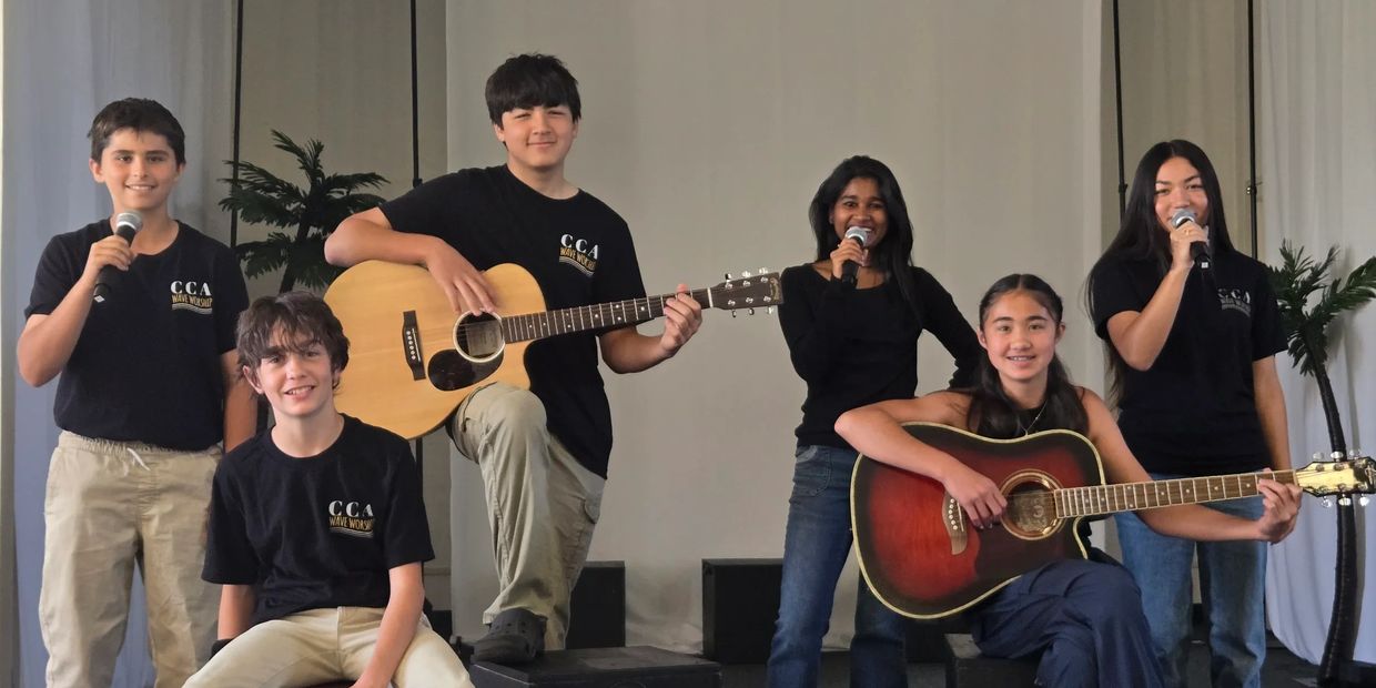 Group of young musicians performing with guitars and microphones on stage.