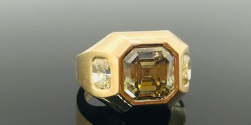 18kt yellow gold gypsy ring with off-color asscher cut diamond and 2 cushion cut side stones