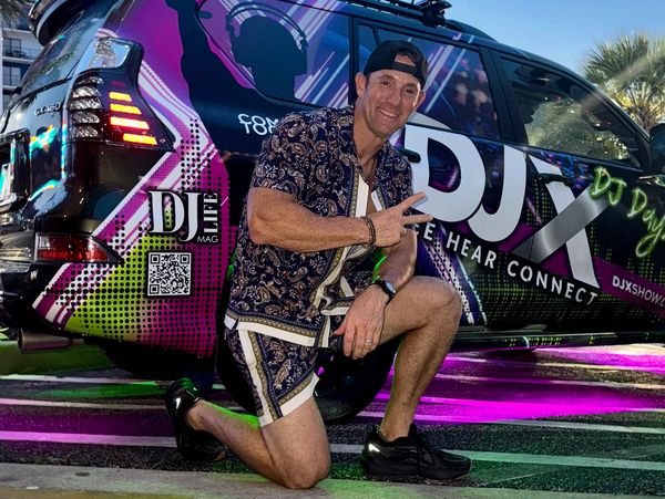 Man posing in front of a vibrant DJ-themed car.
