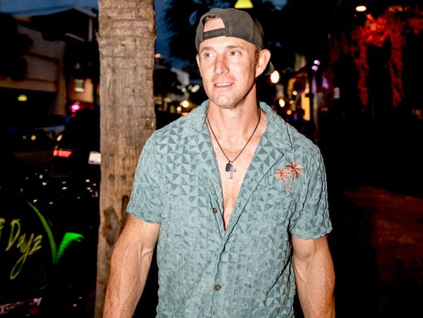 Man in a casual shirt and backward cap at night.