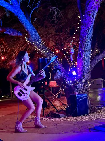 madame harlequin playing bass guitar at local joshua tree party in rhinestone betsy johnson boots