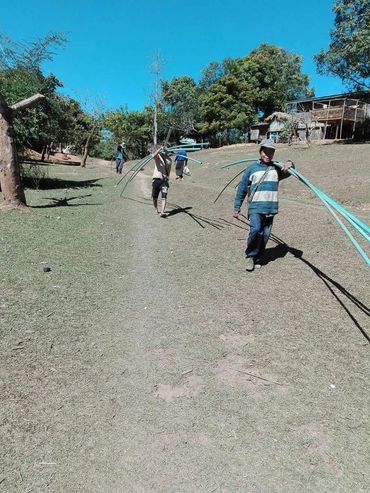 Villagers carrying water pipes on their shoulders