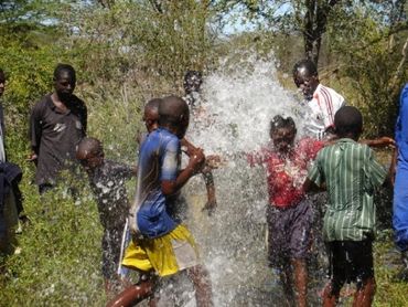 children playing with water from a pipe in the village