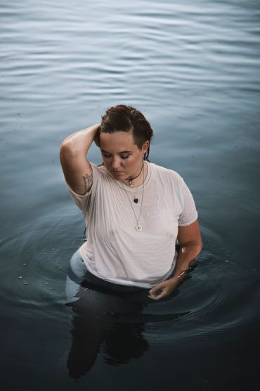 Person standing in water wearing a wet white shirt.