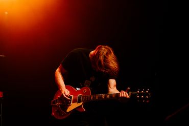 Guitarist passionately playing an electric guitar under warm stage lights.