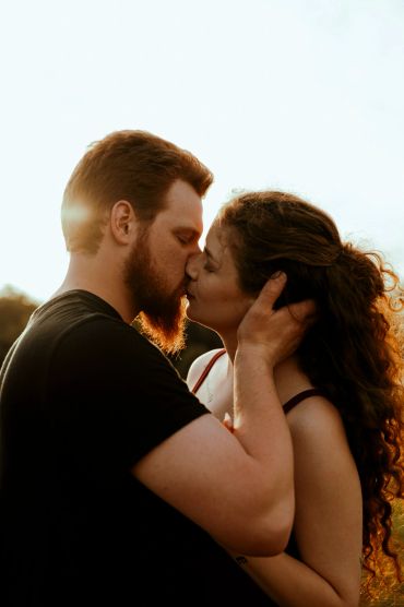 Couple sharing a tender kiss outdoors.
