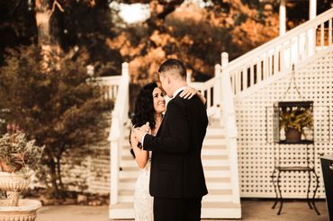 Couple sharing a romantic dance outdoors near white stairs.