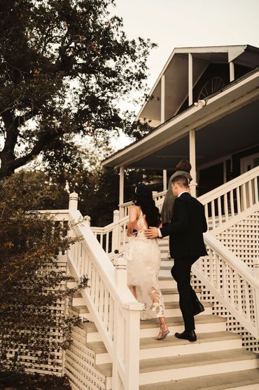 A couple dressed formally ascending white stairs at a PNW house.