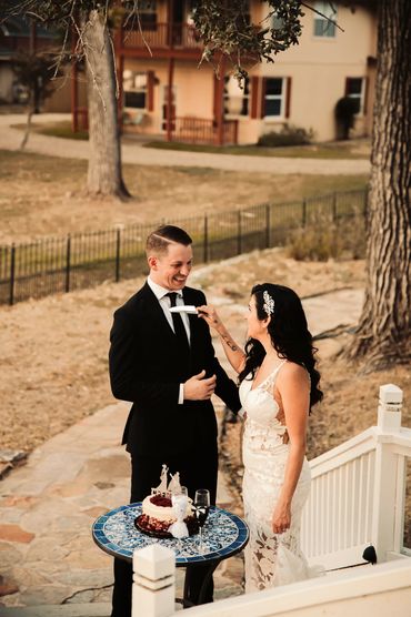 Bride playfully feeding groom cake at outdoor wedding.