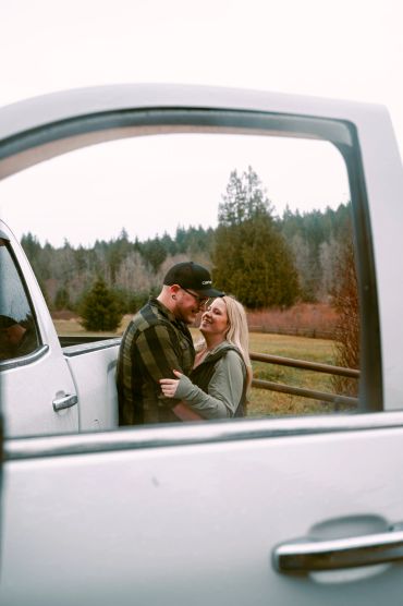 Couple embracing outside near a white vehicle.