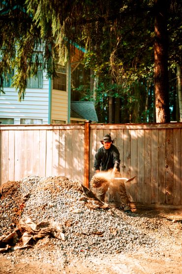 Man shoveling gravel at a construction site.