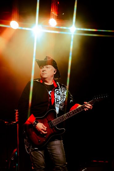 Musician playing electric guitar on stage under bright lights in Tacoma WA