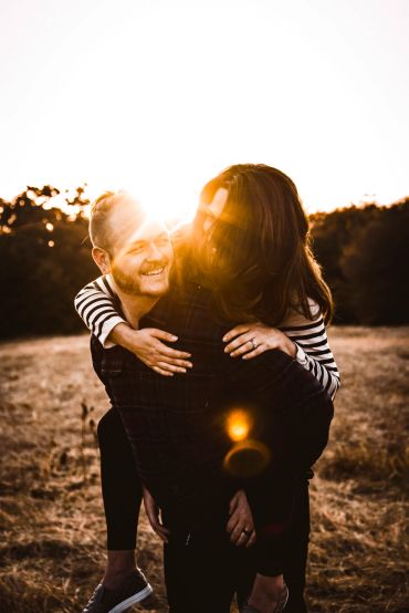 Couple enjoying a piggyback ride at sunset.