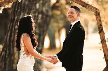 Couple holding hands and smiling during a PNW wedding ceremony outdoors.