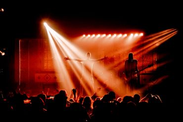Energetic live concert with vibrant orange stage lights and enthusiastic crowd.