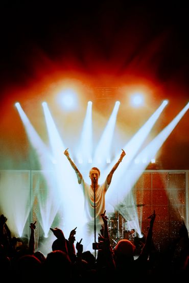 Singer on stage with bright lights and crowd showing middle fingers.