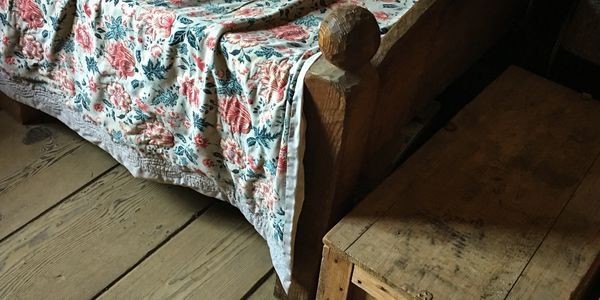 A rustic bed and clothes chest.