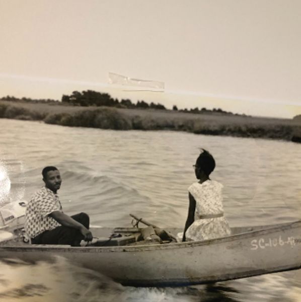 Couple enjoying a boat ride on a calm river in a vintage black and white photo.