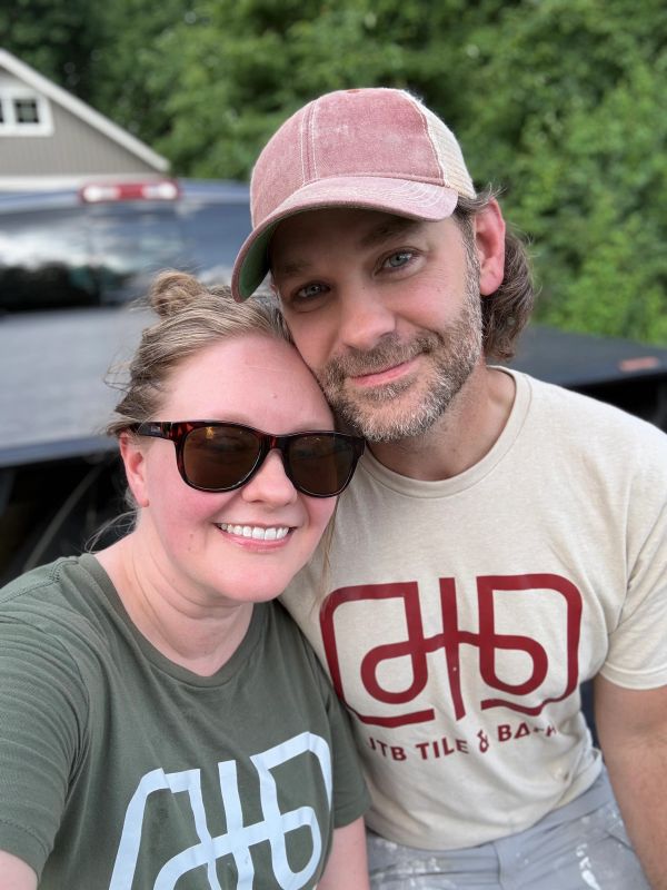 Smiling couple wearing matching logo t-shirts outdoors.