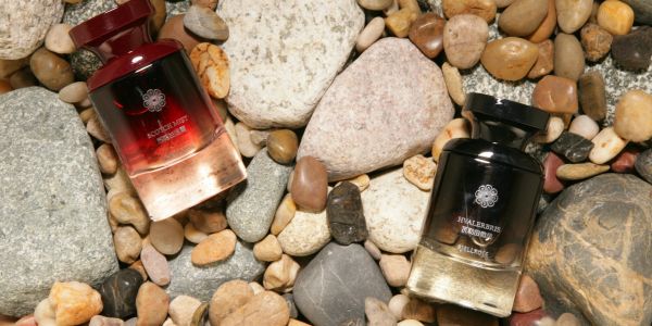 Two perfume bottles on a bed of assorted pebbles and stones.