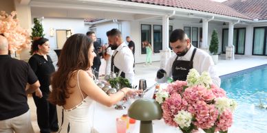 People enjoying a poolside party with drinks and floral decorations.