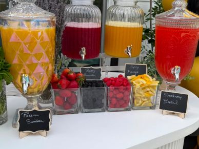 Colorful fruit juices and fresh berries displayed on a white table.