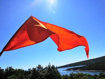 Zastava Sanātana Dharme koja vijori iznad prirodnog krajolika, simbol duhovne prisutnosti 