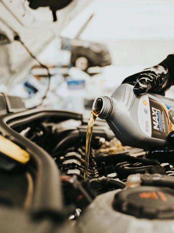 Pouring motor oil into a car engine during maintenance.