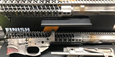 Custom painted rifle parts with a shark mouth design and metallic finish.