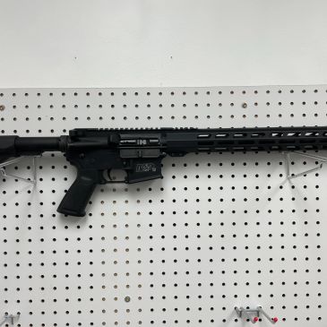 Black semi-automatic rifle mounted on a pegboard wall.