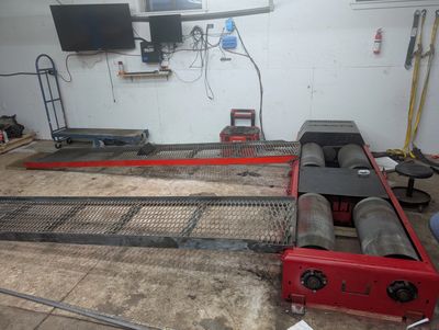 Vehicle dynamometer setup in a workshop with monitors and tools.