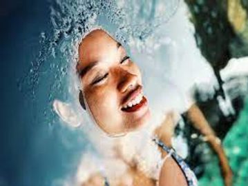 A woman smiling underwater with bubbles around her face.
