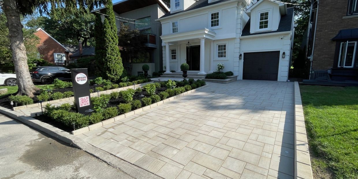 Modern white house with paved driveway and landscaped garden.